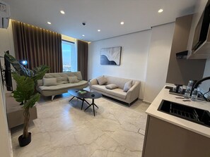 A modern living room with a sofa, coffee table, and a potted plant. - 413 tara-JRE Jabal Al Lweibdeh with stunning view (Amman)