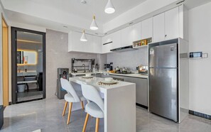 A modern kitchen with a central island, stainless steel appliances, and pendant lighting. - Serene 1-Bedroom Apartment with National Park Views (Nairobi)