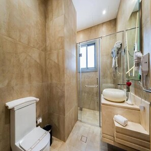 Un baño con inodoro, cabina de ducha de vidrio, lavamanos y espejo.