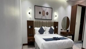 Et moderne hotelværelse med en stor seng, sengeborde, et spejl og et billede i ramme på væggen.