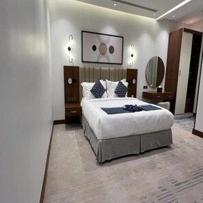 Un dormitorio de hotel moderno con una cama grande, mesitas de noche, un espejo y un cuadro en la pared.