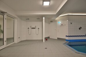 Ein modernes Badezimmer mit Dusche, Toilette und einem Poolbereich.