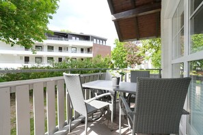 Ein Balkon mit Korbmöbeln, einem Tisch und Stühlen.