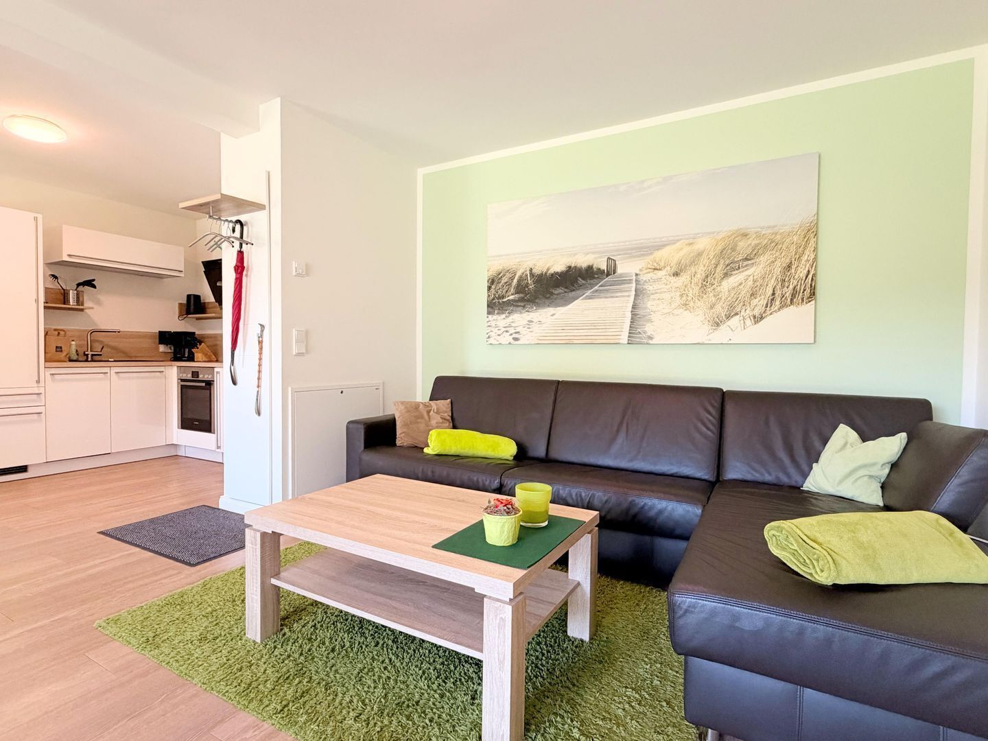 A modern living room with a sofa, a coffee table, and a kitchen in the background.