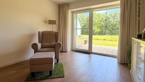 Una habitación con sofá, lámpara y puerta corrediza de vidrio que da a un jardín.