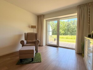 Ein Zimmer mit einer Couch, einer Lampe und einer Glastür, die zu einem Garten führt.