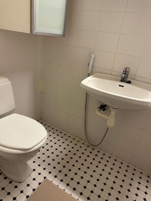 A bathroom with a toilet, a sink, and a tiled floor. - NOT LISTED (Helsinki)