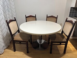 A round dining table with four chairs, a metal base, and a patterned curtain in the background. - NOT LISTED (Helsinki)