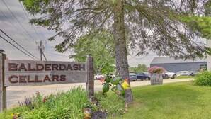 A sign for Balderdash Cellars with a wooden fence, a tree, and a parking lot in the background. - 3 Acres, Mtn Views, Hot Tub, Steps to Winery (Richmond)