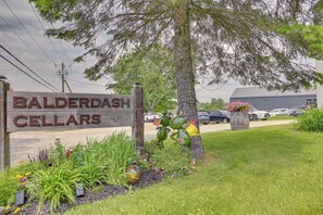 Schild für Balderdash Cellars, mit Holzzaun, Baum und Parkplatz im Hintergrund.