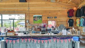A rustic wooden interior with a counter displaying various items, a sign for 'MERLOT', and a view of the outdoors. - 3 Acres, Mtn Views, Hot Tub, Steps to Winery (Richmond)