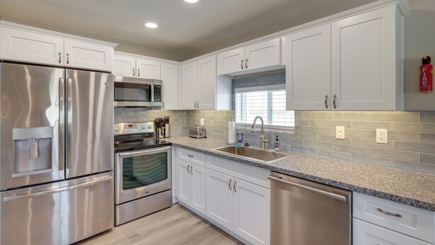 A modern kitchen with stainless steel appliances, white cabinetry, and a granite countertop. - Stylish Maricopa Cottage w/ Mtn Views & Grill! (Maricopa)