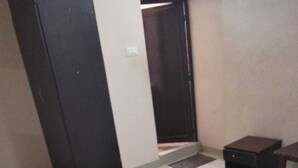 Una habitación con una silla negra, una mesita, una puerta y piso de baldosas.