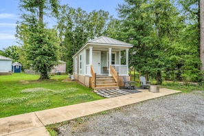 A small, single-story cabin with a porch, a staircase, and a seating area with a table and chairs.