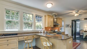 A kitchen with a large island, wooden chairs, and a view of the outdoors through the windows. - Walk to Dtwn! Historic & Elegant Gem in Charlotte (Charlotte)