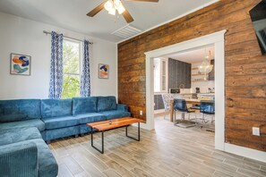 Ein Wohnzimmer mit einer Eckcouch, einem Couchtisch aus Holz und einem Essbereich mit Stühlen und Tisch.