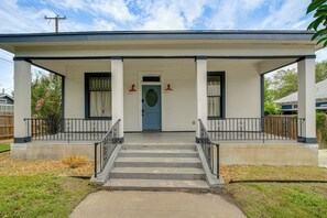 Ein zweistöckiges Haus mit Veranda, einer Haustür und einer Treppe, die zum Eingang führt.
