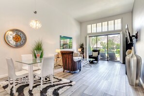 A modern interior with a dining area, a large window, and a view of the outdoors. - PGA West La Quinta Condo for Golf Tournament Stays (La Quinta)