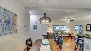 A dining area with a wooden table, chairs, and a hanging light fixture. - Newly Remodeled, Great Porches, and Dog Friendly (Port O'Connor)