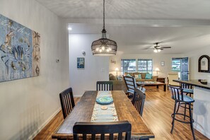 A dining area with a wooden table, chairs, and a hanging light fixture. - Newly Remodeled, Great Porches, and Dog Friendly (Port O'Connor)
