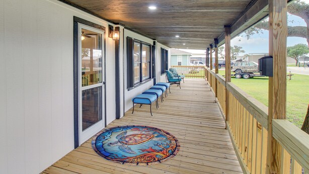 A covered porch with a row of blue chairs, a wooden deck, and a decorative rug. - Newly Remodeled, Great Porches, and Dog Friendly (Port O'Connor)