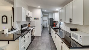 A modern kitchen with white cabinets, black countertops, and stainless steel appliances. - Newly Remodeled, Great Porches, and Dog Friendly (Port O'Connor)