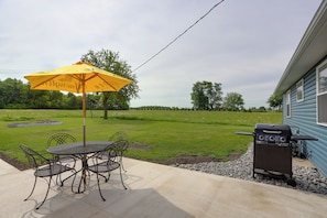Eine Terrasse mit Tisch und Stühlen, einem gelben Sonnenschirm und einem Grill.