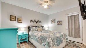 A bedroom with a bed, a nightstand, a ceiling fan, and wall art. - Steps to Ocean! Family-Friendly Carolina Beach Gem (Carolina Beach)