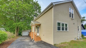 A two-story house with a front porch, a garage, and a large tree in the background. - Fall Escape! Waterfront Chain O'Lakes Hideaway (Spring Grove)