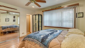 A bedroom with a bed, a ceiling fan, a window with blinds, and a mirror. - Fall Escape! Waterfront Chain O'Lakes Hideaway (Spring Grove)