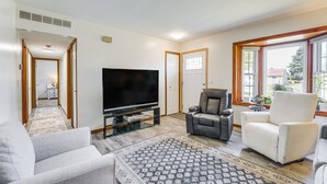 Ein Wohnzimmer mit Flachbildfernseher, zwei Sofas, einem Couchtisch und einem Teppich mit Muster.