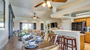 Una cocina amplia con isla central, mesa de comedor de madera y taburetes de bar.