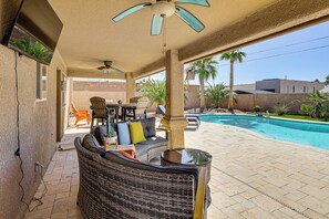 Ein überdachter Patio-Bereich mit Pool, Korbmöbeln und Deckenventilator.