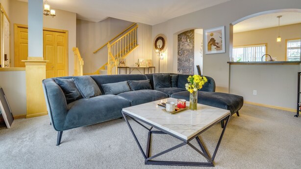 A living room with a sectional sofa, a coffee table, and a staircase leading to another level. - Spacious & Quiet Townhome In the Twin Cities (Roseville)
