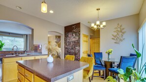 A modern kitchen with a granite countertop, wooden cabinets, and a dining area with blue chairs and a table. - Spacious & Quiet Townhome In the Twin Cities (Roseville)