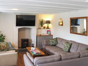 Ein Wohnzimmer mit Kamin, Sofa, Couchtisch und einem an der Wand befestigten Flachbildfernseher.