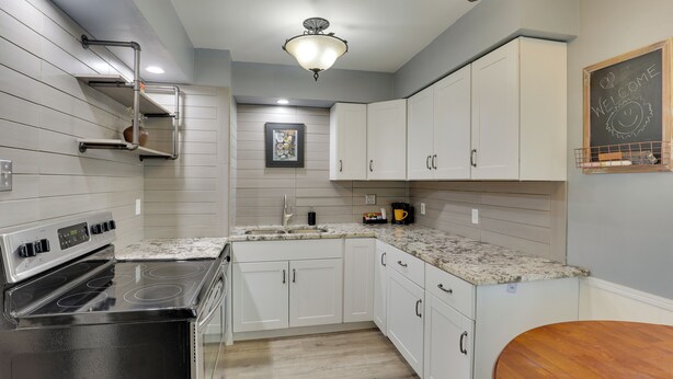 A kitchen with white cabinets, a black stove, and a wooden dining table.
