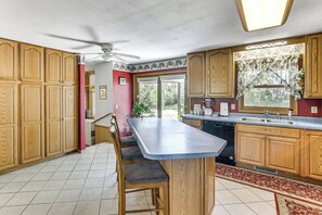 A kitchen with wooden cabinets, a dining table, and a ceiling fan. - Explore Badlands Nat'l Park: Family Home w/ Patio (Kadoka)