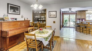 Ein Essbereich mit Klavier, einem Tisch mit Blumenmuster-Tischdecke und einem Bücherregal mit Dekoration.