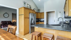 Una cocina con armarios de madera, un refrigerador de acero inoxidable, un lavamanos y un comedor con mesa y sillas de madera.