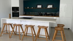 Et moderne køkken med en central ø, barstole, mikrobølgeovn og kaffemaskine.