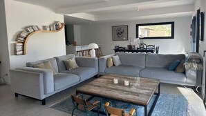 En moderne stue med en grå hjørnesofa, et træsofabord og en reol.