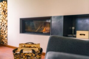Ein Kamin mit Holzscheiten, eine Couch und ein Aufbewahrungsfach.