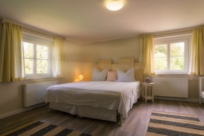 Ein Schlafzimmer mit einem Bett, zwei Nachttischen, einem Fenster und einer Heizung.
