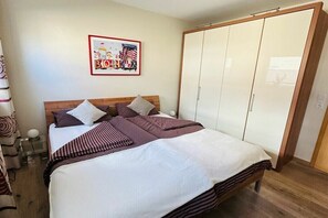 Ein Schlafzimmer mit einem Bett, Kissen, einem Kleiderschrank und einem gerahmten Bild an der Wand.