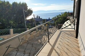 A balcony with a metal railing overlooking a residential area and a distant body of water. - Apartments Hošnjak (3) (Njivice)