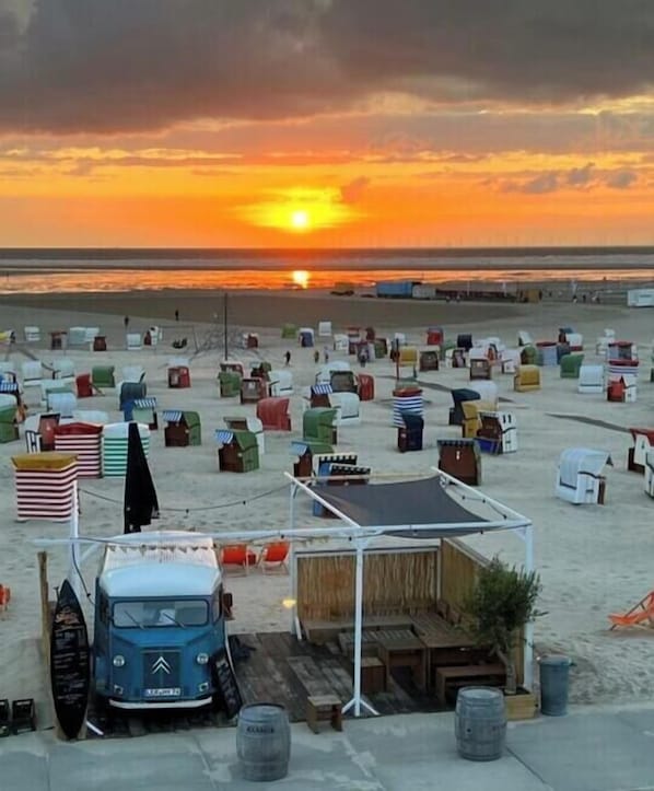 A beachside setting with beach chairs, a tent, and a blue vehicle. - Holiday apartment with 2 bedrooms (Borkum)