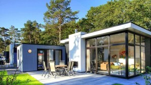 A modern house with a patio, a small shed, and a large glass-enclosed room. - Holiday Home in Olburgen With Terrace (Olburgen)
