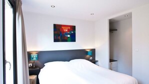 A hotel room with a bed, two bedside lamps, a wall art piece, and a door leading to another room. - Holiday Home in Olburgen With Terrace (Olburgen)