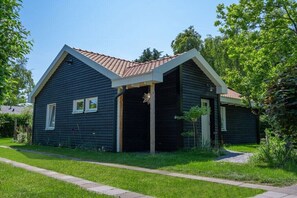 Ein zweistöckiges Haus mit dunkler Fassade, einem roten Ziegeldach und einer Veranda.